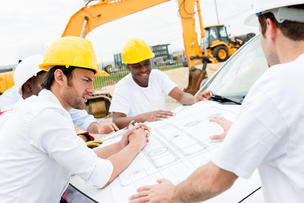 Group of civil engineers working on a construction and looking at blueprints Group of civil engineers working on a construction and looking at blueprints
